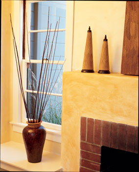 Kelly gave the original living room fireplace a new look with a plastered surround and an adjacent display shelf. She plastered with Structolite—a durable gypsum plaster—then painted the walls and fireplace surround with a light-colored clay containing bits of shiny mica, and finally applied a translucent casein glaze.